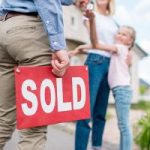 Ocean County real estate agent holding a sold sign outside of a home that recently had Ocean County tree service