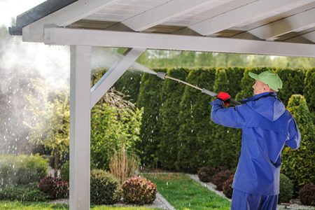 Toms River pressure washing professional in a blue waterproof suit cleaning a gazebo