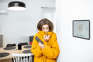Person in yellow winter coat looking at large smart home display showing thermostat